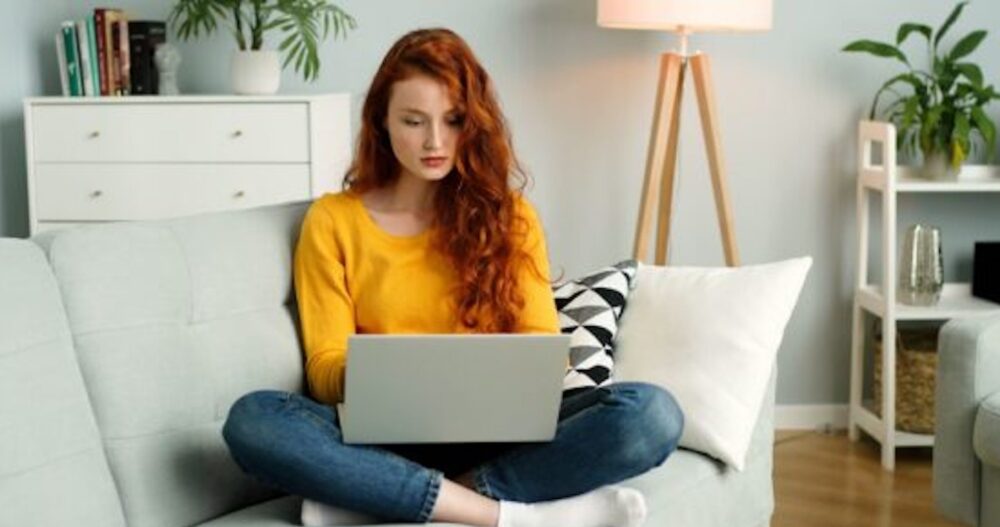 Woman on couch with laptop computer doing teletherapy