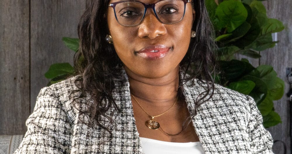 Headshot of Ade Odujole, APRN, CNP, dressed in a white top and patterned business jacket.