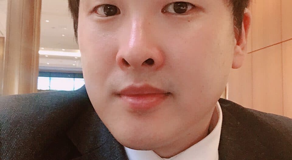 Headshot of a man wearing a white collared shirt and dark jacket.