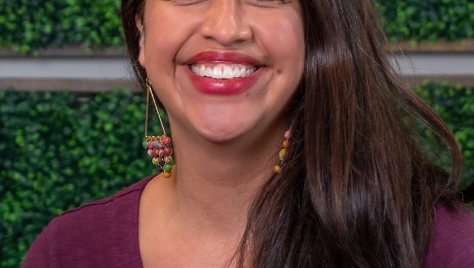 Headshot of Caryn Bittinger, MA, R-DMT, smiling, dressed in a maroon top, wearing decorative earrings.