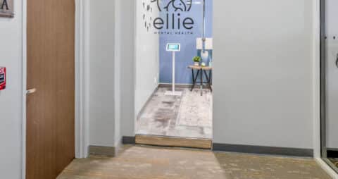 An interior photo of an Ellie Mental Health Therapy Clinic office with large glass window that has the Ellie Mental Health logo on.it.