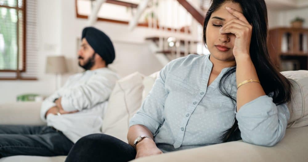 Woman sitting next to a man on the couch with her head in her hands