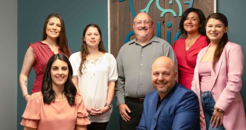 Several Ellie Mental Health professionals from the Morristown, New Jersey therapy clinic standing in front of an Ellie Mental Health sign.