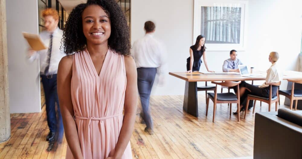 woman standing in an office surrounded by other people