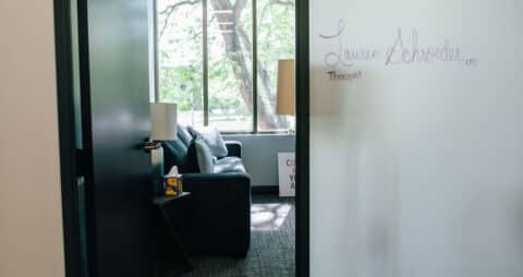 An interior photo looking into an Ellie Mental Health Therapy Clinic office with the name Lauren Schroeder, Therapist, written on the wall in purple marker.
