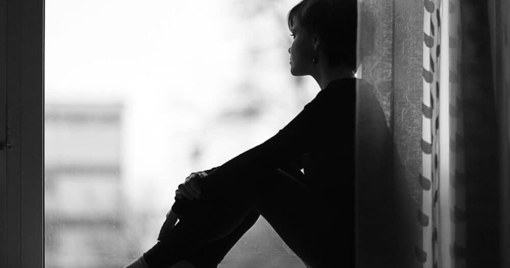 Woman sitting looking out the window longingly