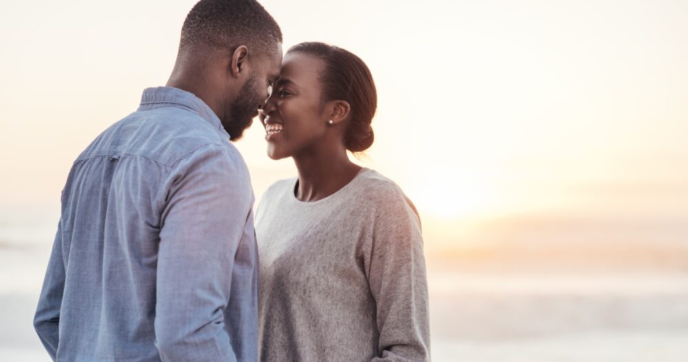 Couple holding hands and looking into each others eyes during sunset