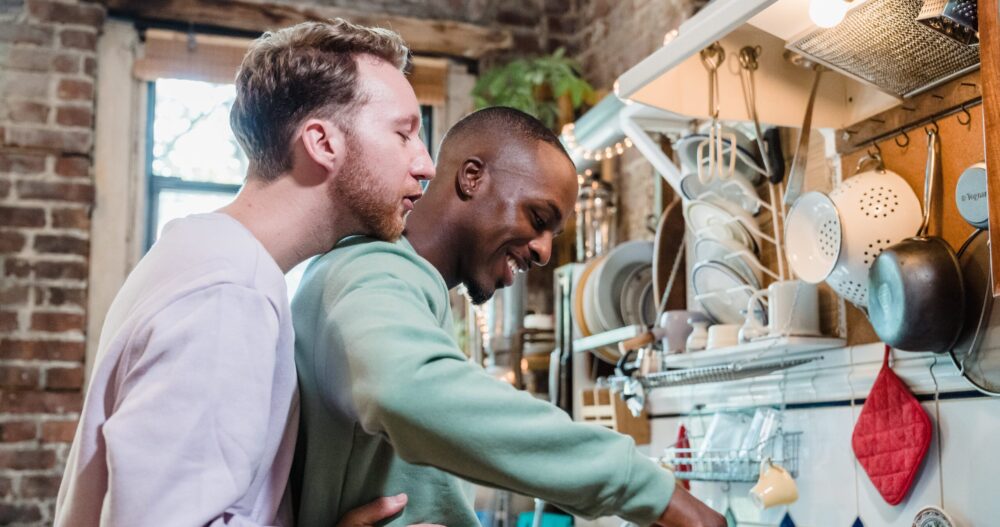 Two men hugging and smiling while cooking dinner