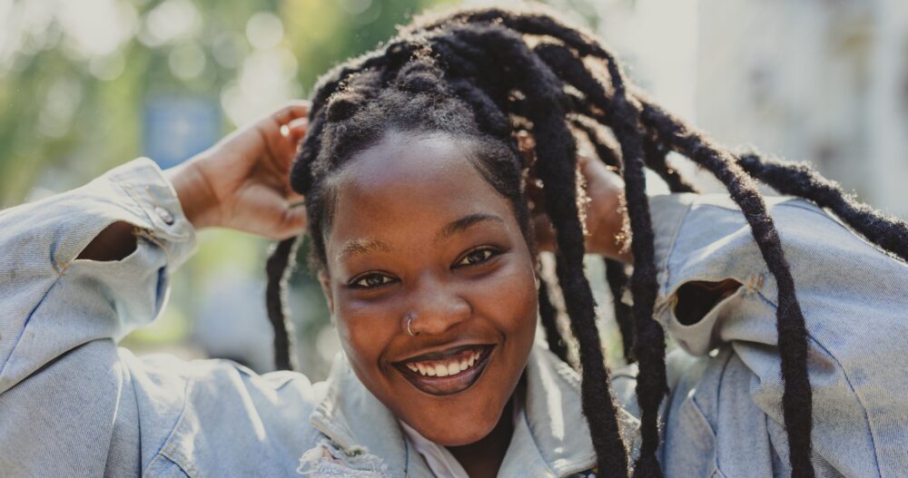 Black female presenting person smiling outside