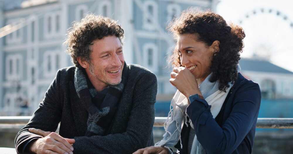 Man and woman standing outside talking and smiling