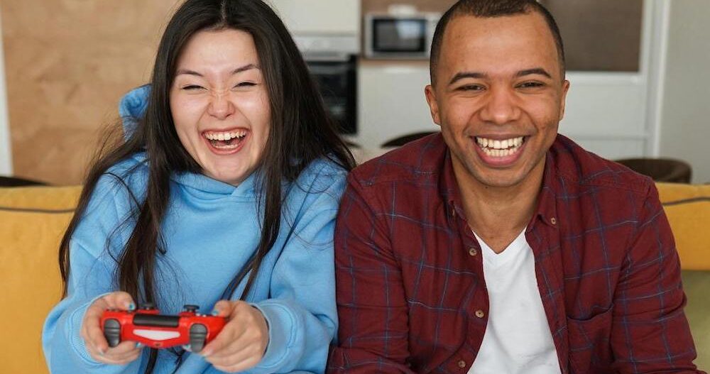 Man and woman sitting on the couch playing video games together