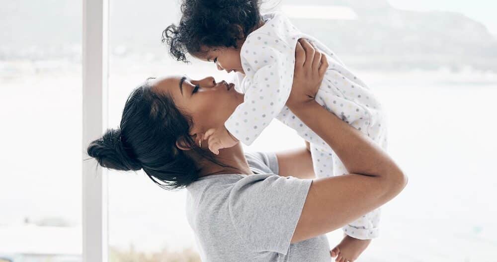 A mother holding her baby daughter at home.