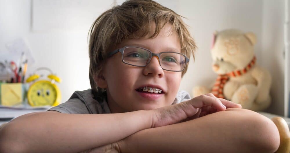 Close up portrait of tween boy with braces and eyeglasses smiling