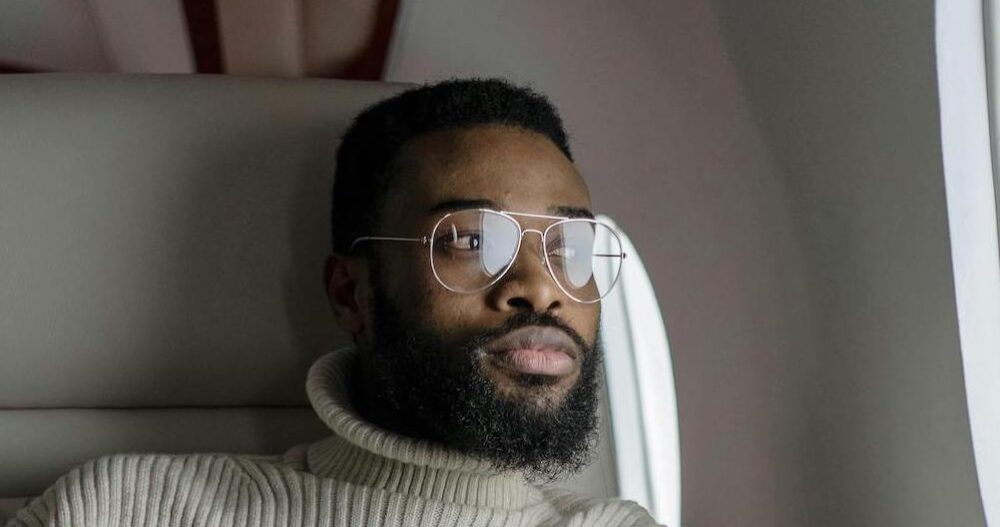 Man with glasses sitting on a plane looking out the window